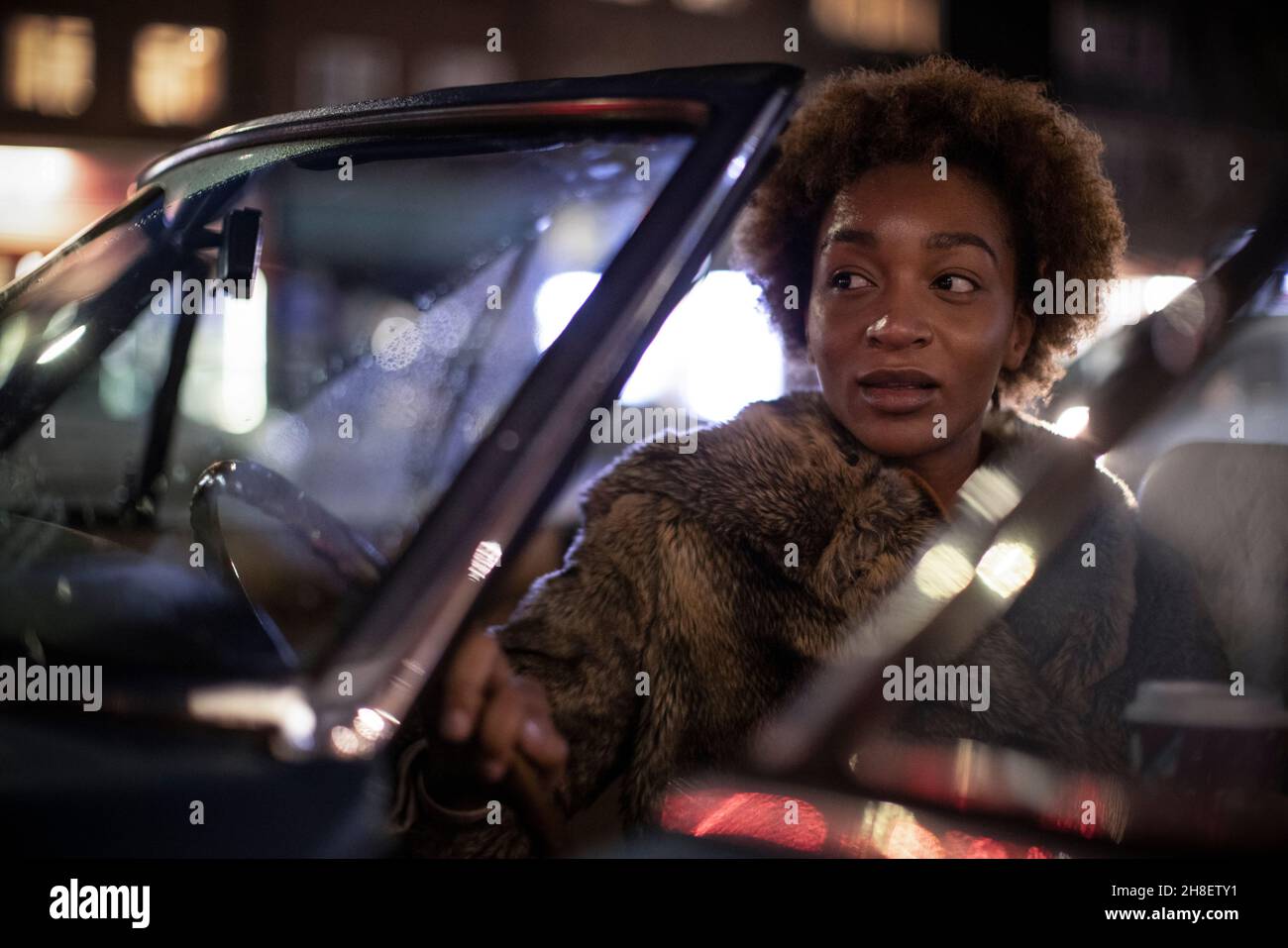 Jeune femme qui sort du cabriolet la nuit Banque D'Images