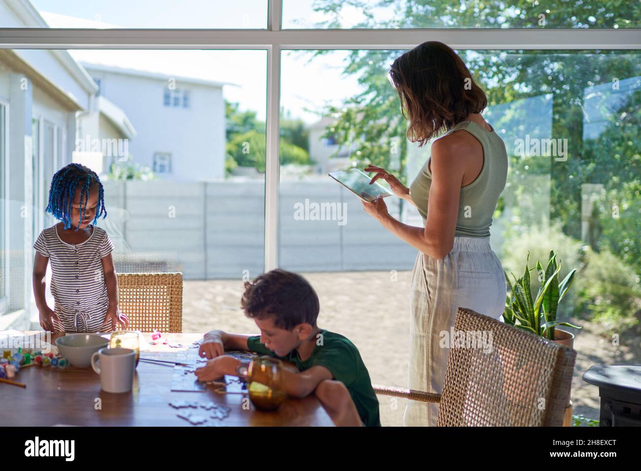 Mère et enfants travaillant et jouant à la table de salle à manger Banque D'Images