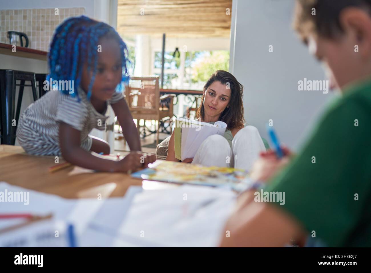 Mère et enfants lisant et coloriant à la maison Banque D'Images