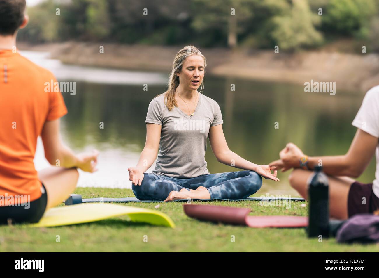 Instructeur faisant la pose de lotus pendant un cours de yoga dans un parc Banque D'Images