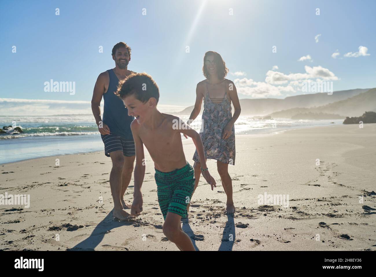 Bonne famille jouant sur la plage ensoleillée d'été Banque D'Images