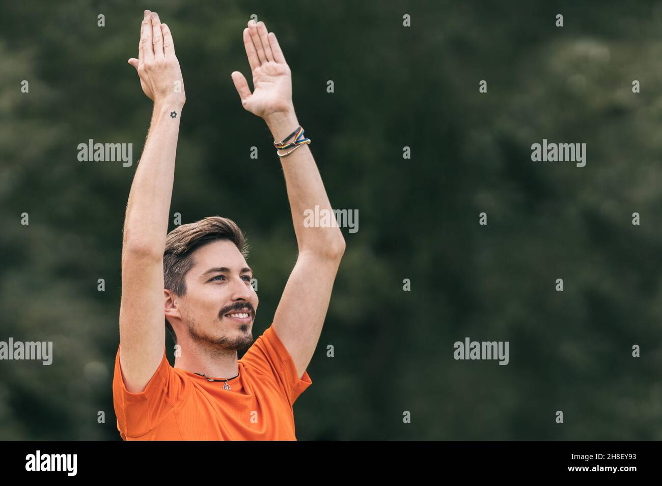 Homme avec une expression heureuse faisant du yoga à l'extérieur Banque D'Images
