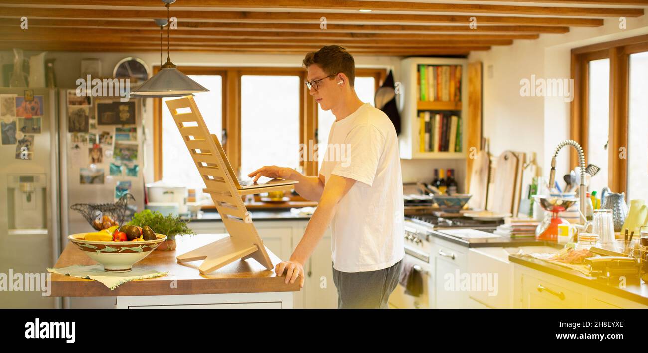 Homme travaillant au bureau d'un ordinateur portable dans la cuisine Banque D'Images