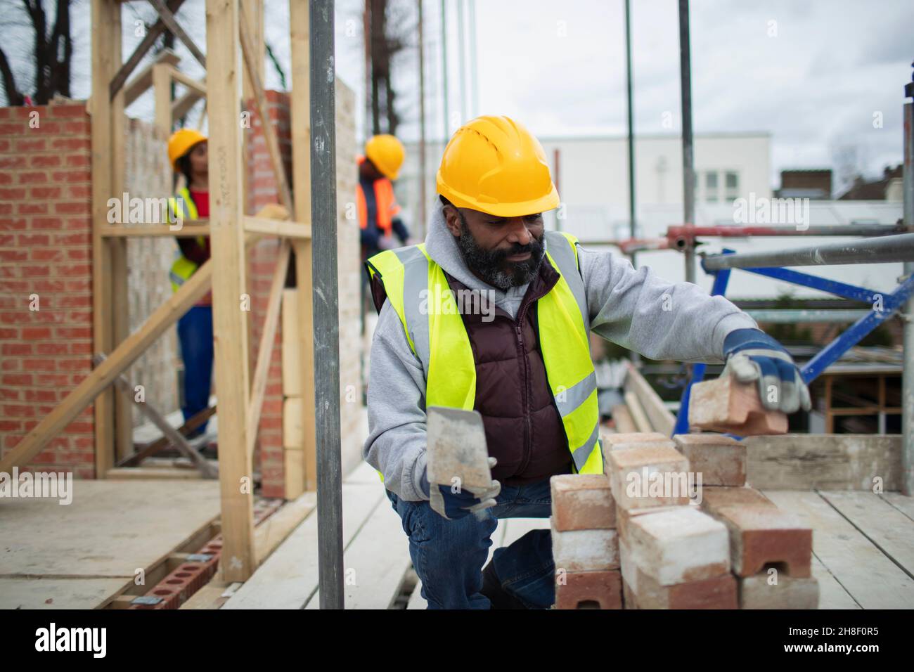 Ouvrier de la construction mâle posant des briques sur le chantier de construction Banque D'Images