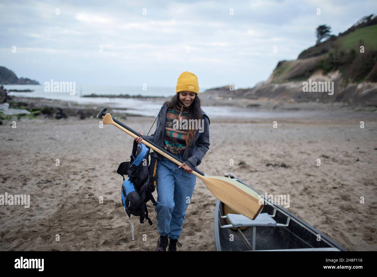 Jeune femme avec des oars en canoë sur la plage d'hiver Banque D'Images