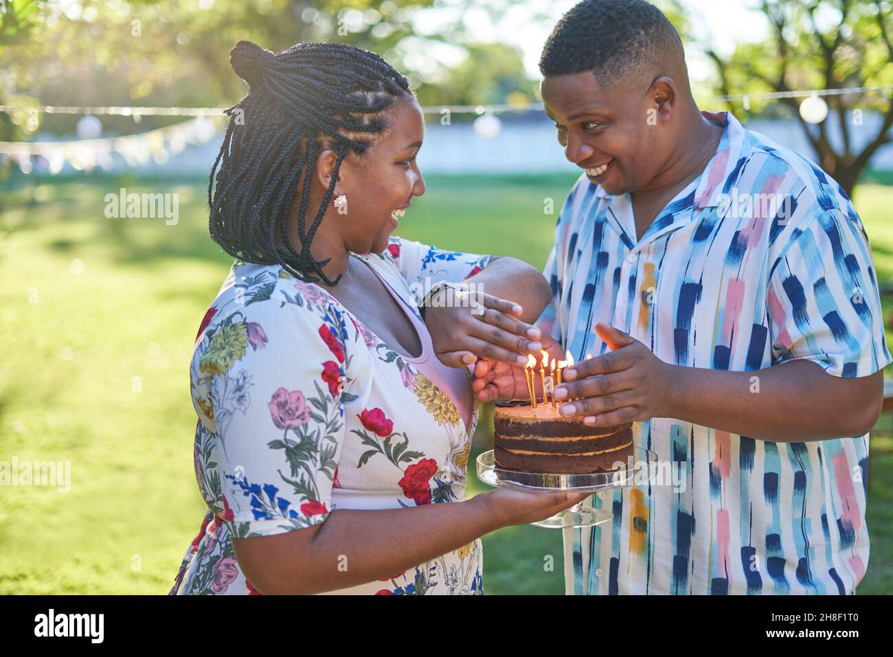 Joyeux couple célébrant son anniversaire avec un gâteau et des bougies dans le parc Banque D'Images