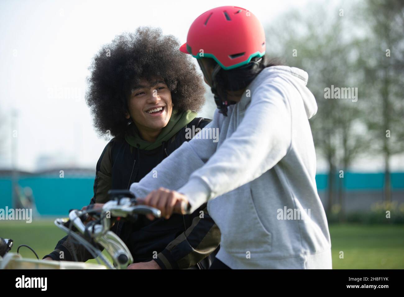Des amis adolescents heureux à vélo dans le parc Banque D'Images