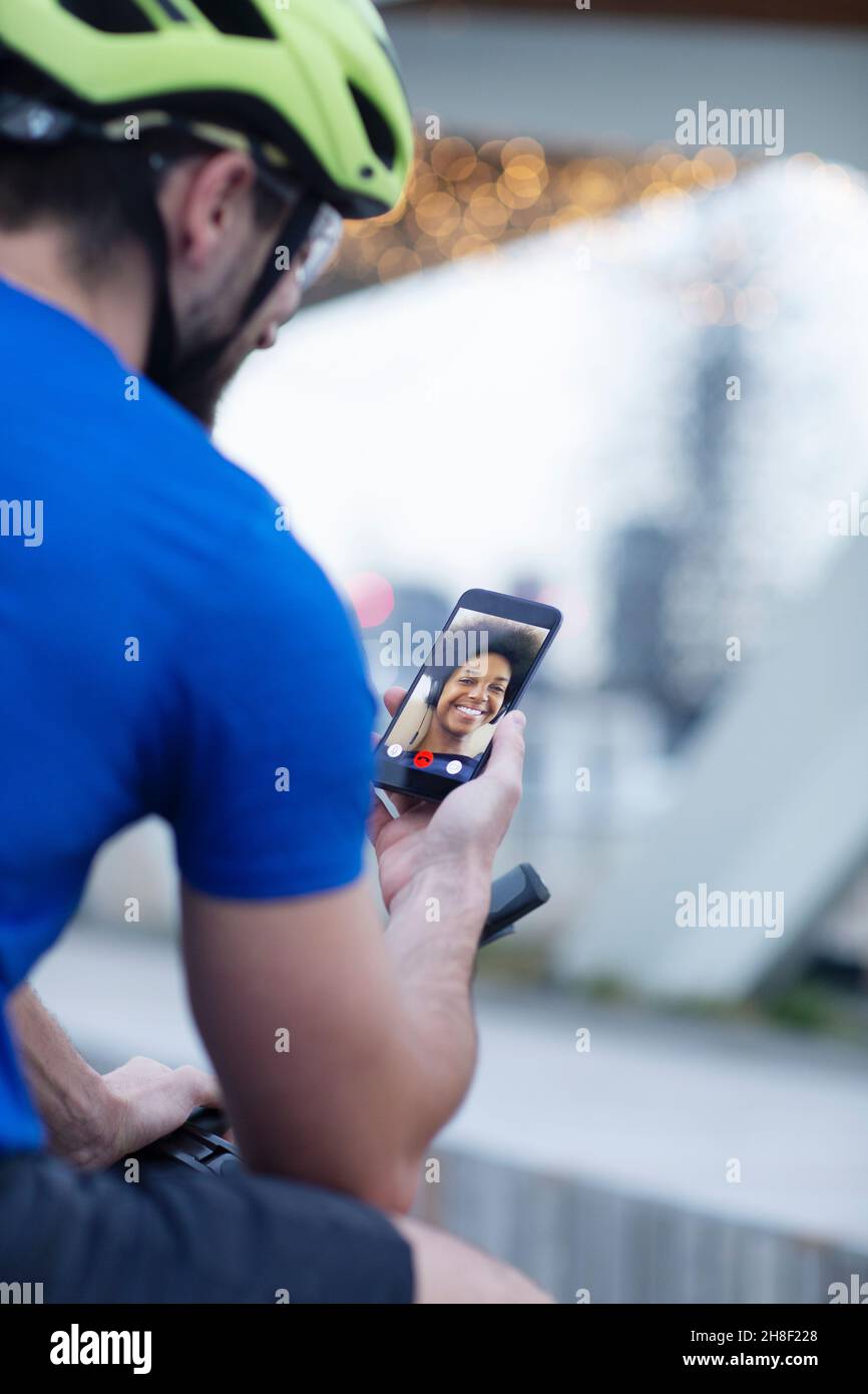 Homme dans un casque de vélo chat vidéo avec une petite amie Banque D'Images Homme dans un casque de vélo chat vidéo avec une petite amie Banque D'Images