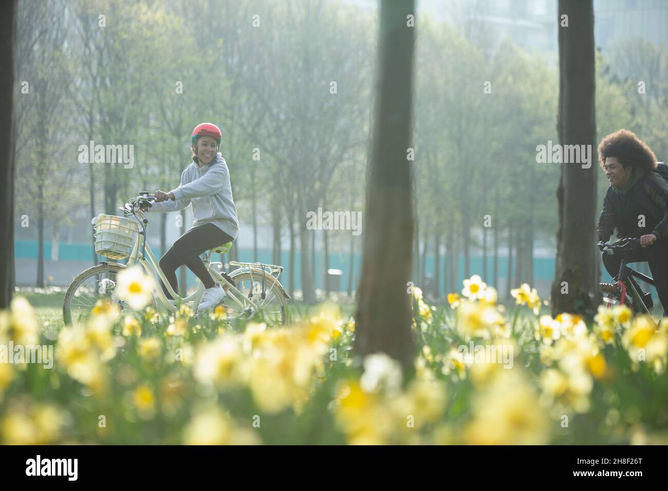 Des amis adolescents heureux à vélo dans un parc de printemps ensoleillé Banque D'Images Des amis adolescents heureux à vélo dans un parc de printemps ensoleillé Banque D'Images