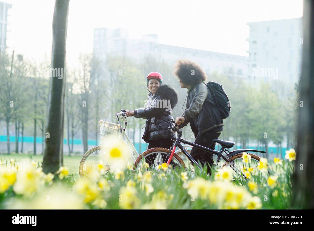 Des amis adolescents avec des vélos dans le parc de printemps urbain ensoleillé Banque D'Images Des amis adolescents avec des vélos dans le parc de printemps urbain ensoleillé Banque D'Images