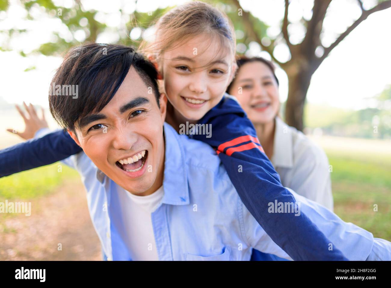 Famille heureuse avec fille jouant ensemble dans le parc Banque D'Images