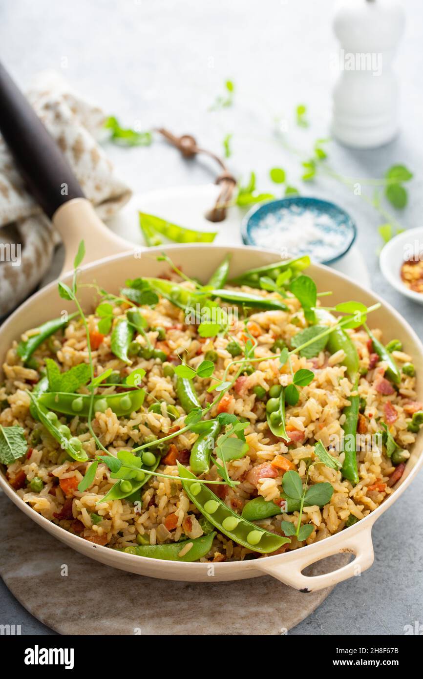 Petit déjeuner riz frit avec pois verts et carottes et pousses de pois frais dans une poêle Banque D'Images