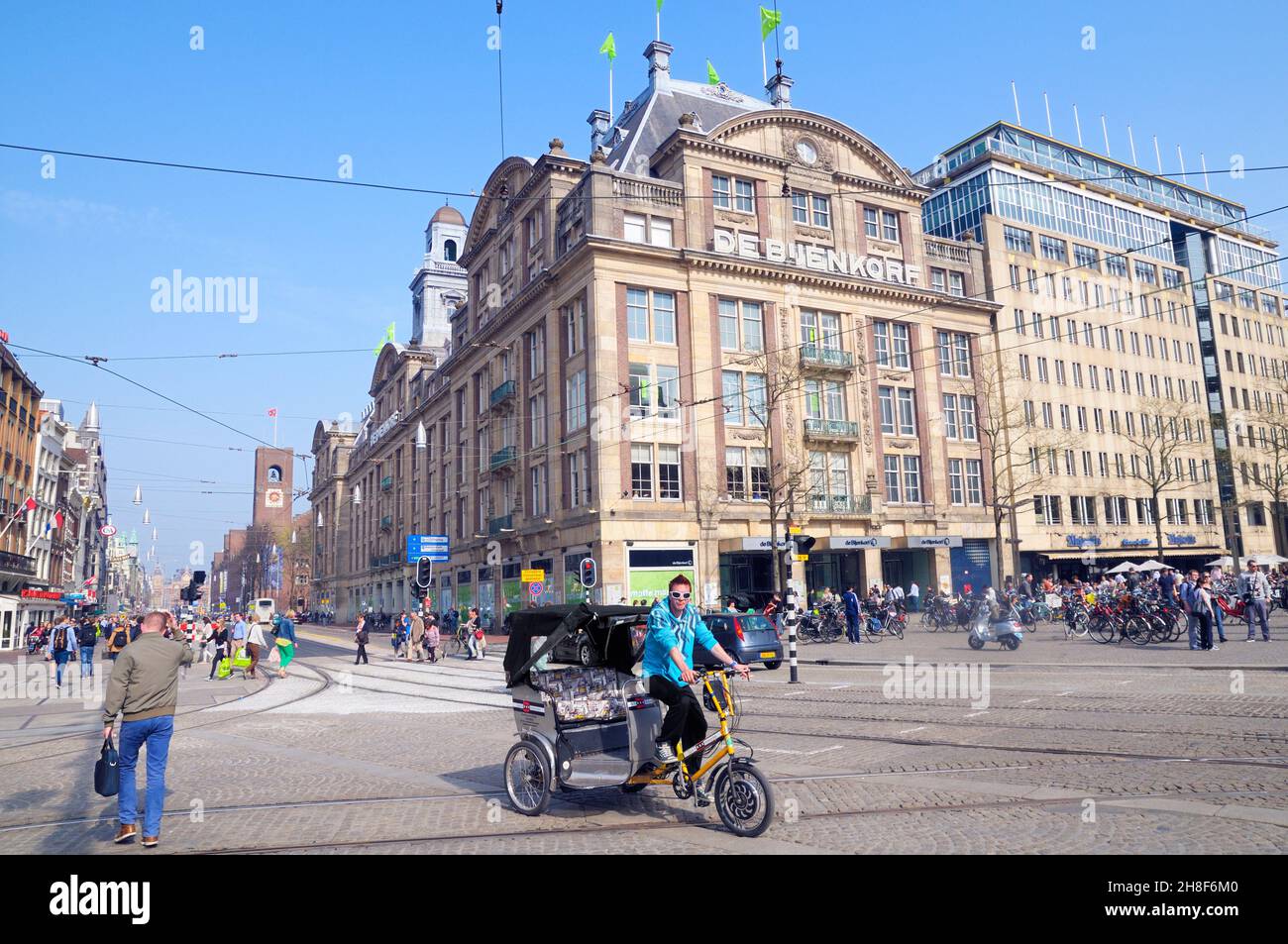 Un chauffeur de vélo de taxi en pousse-pousse passe devant le grand magasin de Bijenkorf, à l'angle de la place Dam et de la rue Damrak, Amsterdam, Hollande-Nord, pays-Bas Banque D'Images