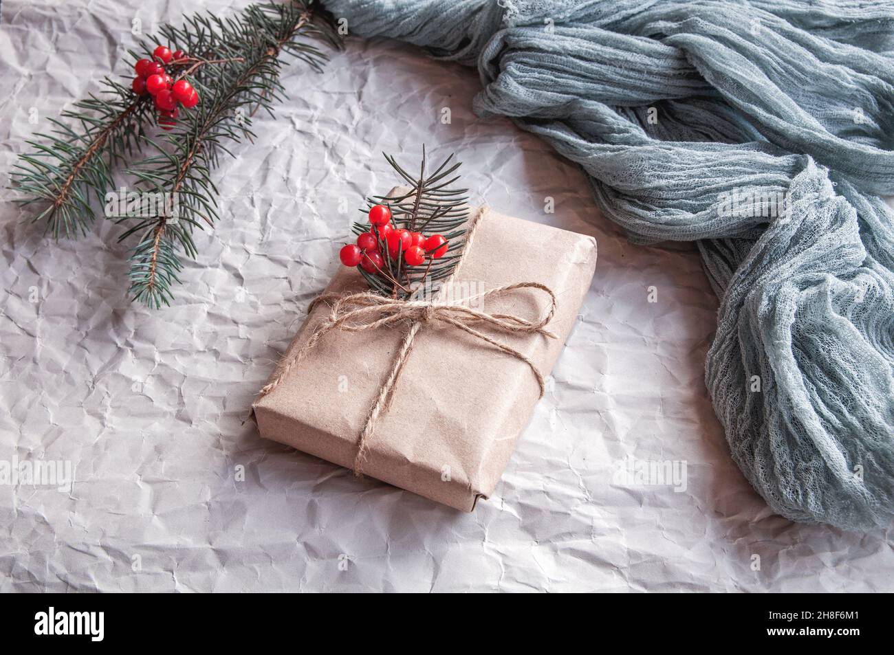 Boîte cadeau à côté de la nappe vintage gris et feuilles d'épinette avec baies rouges sur fond noir, composition festive sur fond clair Banque D'Images