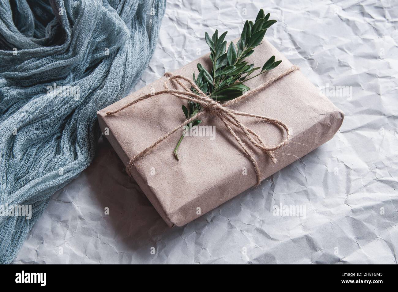 Boîte cadeau à côté de la nappe vintage gris et feuilles d'épinette avec baies rouges sur fond blanc, composition festive sur fond clair Banque D'Images