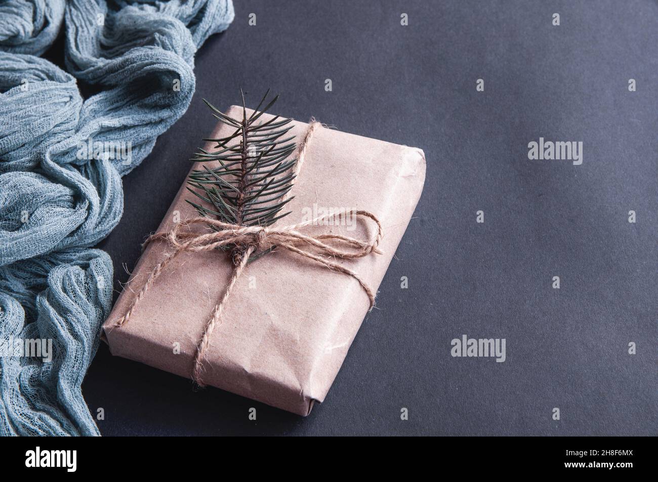 Boîte cadeau à côté du chemin de table vintage gris sur fond noir, composition festive sur papier foncé Banque D'Images