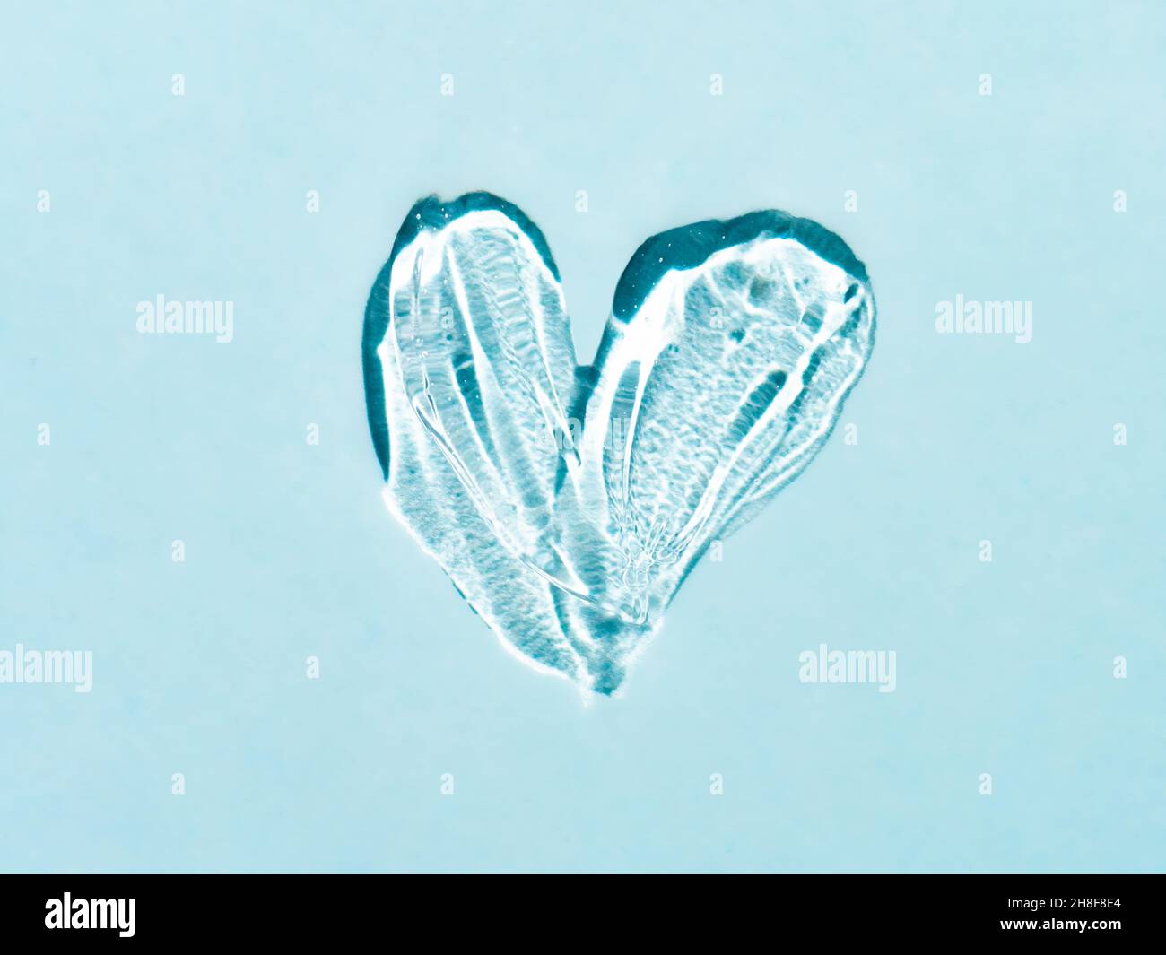 Gel liquide texture de tache cosmétique en forme de coeur sur fond bleu.Esthétique belle texture frottis transparent gel de peau ou masque de visage comme le coeur.Vue de dessus ou plan de travail Banque D'Images
