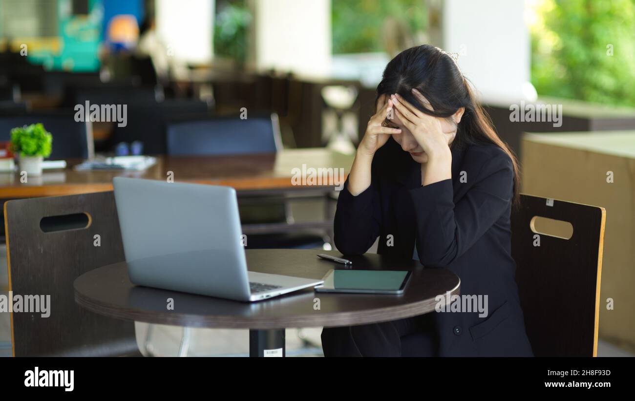 Femme d'affaires stressée, préoccupée par les revenus financiers de son entreprise, travaillant sur un ordinateur portable au bureau. Banque D'Images
