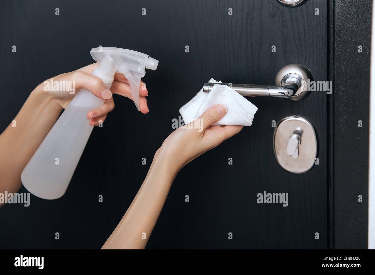 Nettoyage des poignées de porte noires avec une lingette humide antiseptique.Femme main utilisant une serviette pour nettoyer la liaison de la porte de la chambre à la maison.Désinfectez la prévention des surfaces dans Banque D'Images