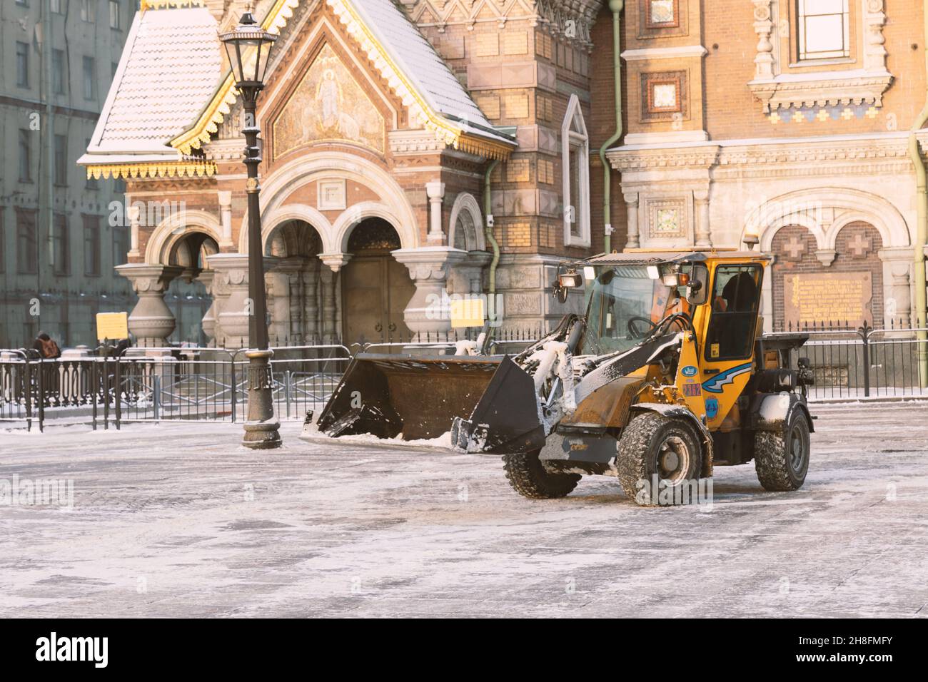 Saint-Pétersbourg, Russie - 16 janvier 2021 : le tracteur jaune mille après la neige dégage la route et la rue près de l'église du Sauveur sur le sang Banque D'Images