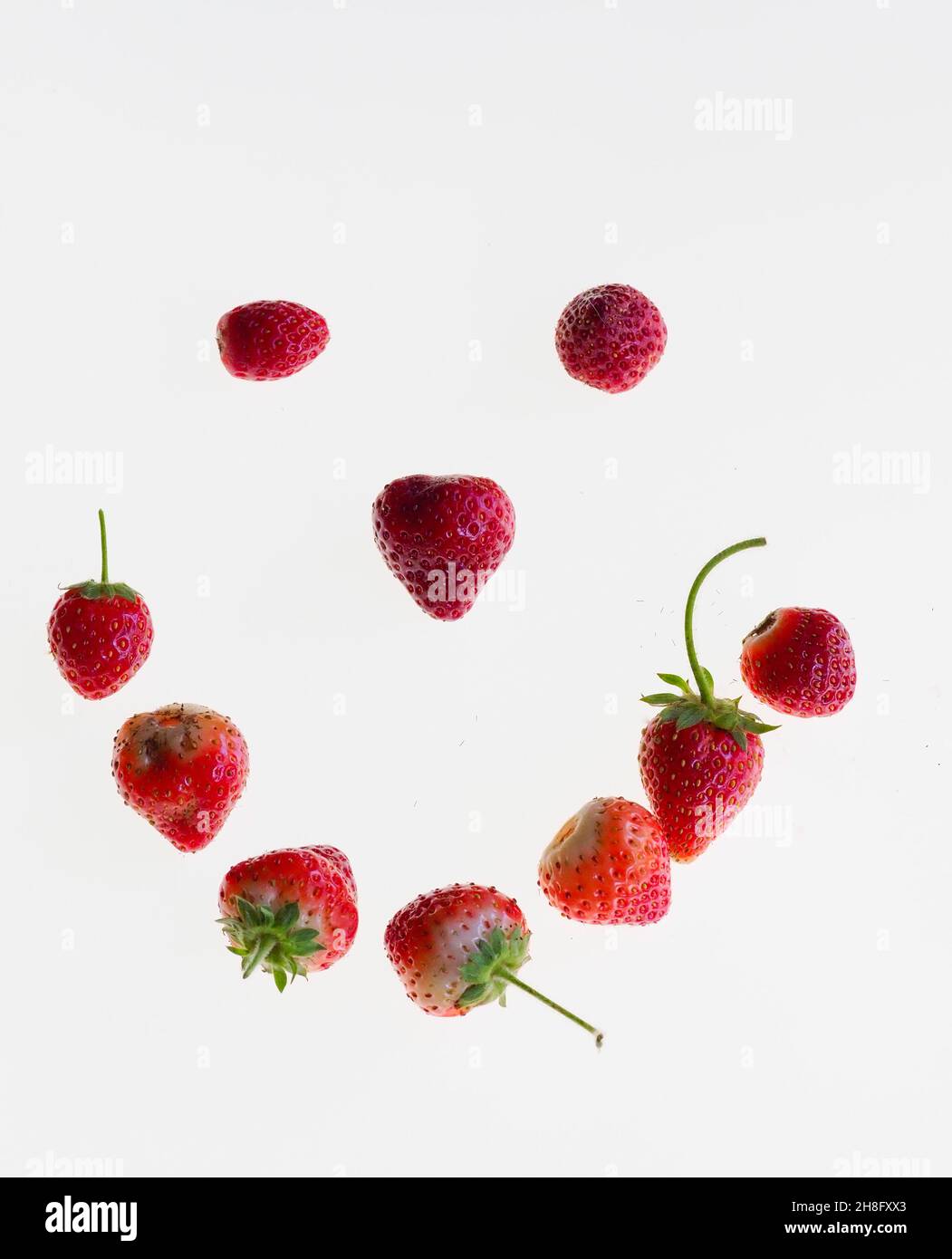 une photo studio d'un visage souriant composé de fraises isolées sur fond blanc Banque D'Images