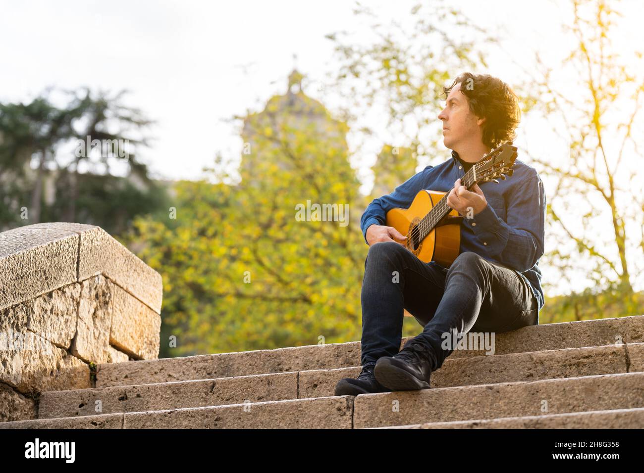 Homme d'âge moyen jouant de la guitare espagnole sur quelques escaliers dans la rue Banque D'Images