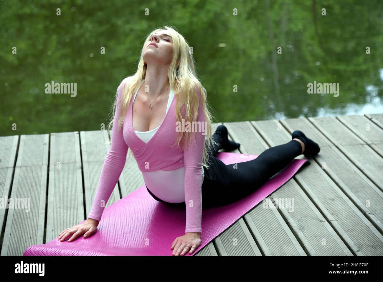 Jeune et mince femme s'exerçant dans le parc avec étang.Femme polonaise faisant un peu de yoga et d'étirement. Banque D'Images