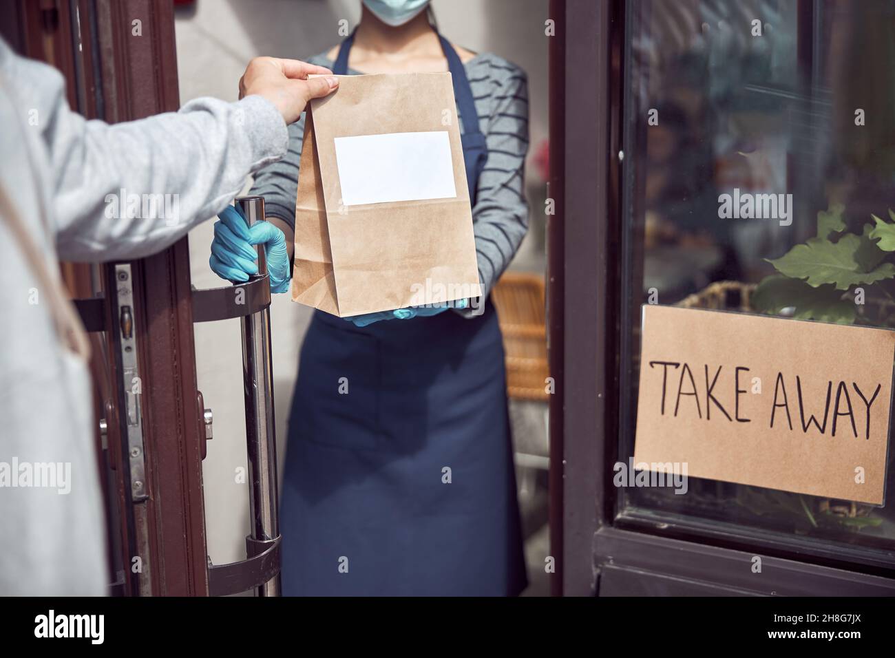 Un employé de café asiatique donne un repas à emporter à l'extérieur tout en restant verrouillé Banque D'Images