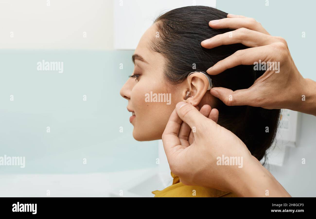 Installation d'une prothèse auditive sur l'oreille d'une femme à la clinique d'audition, vue rapprochée, vue latérale.Traitement de la surdité, solutions auditives Banque D'Images