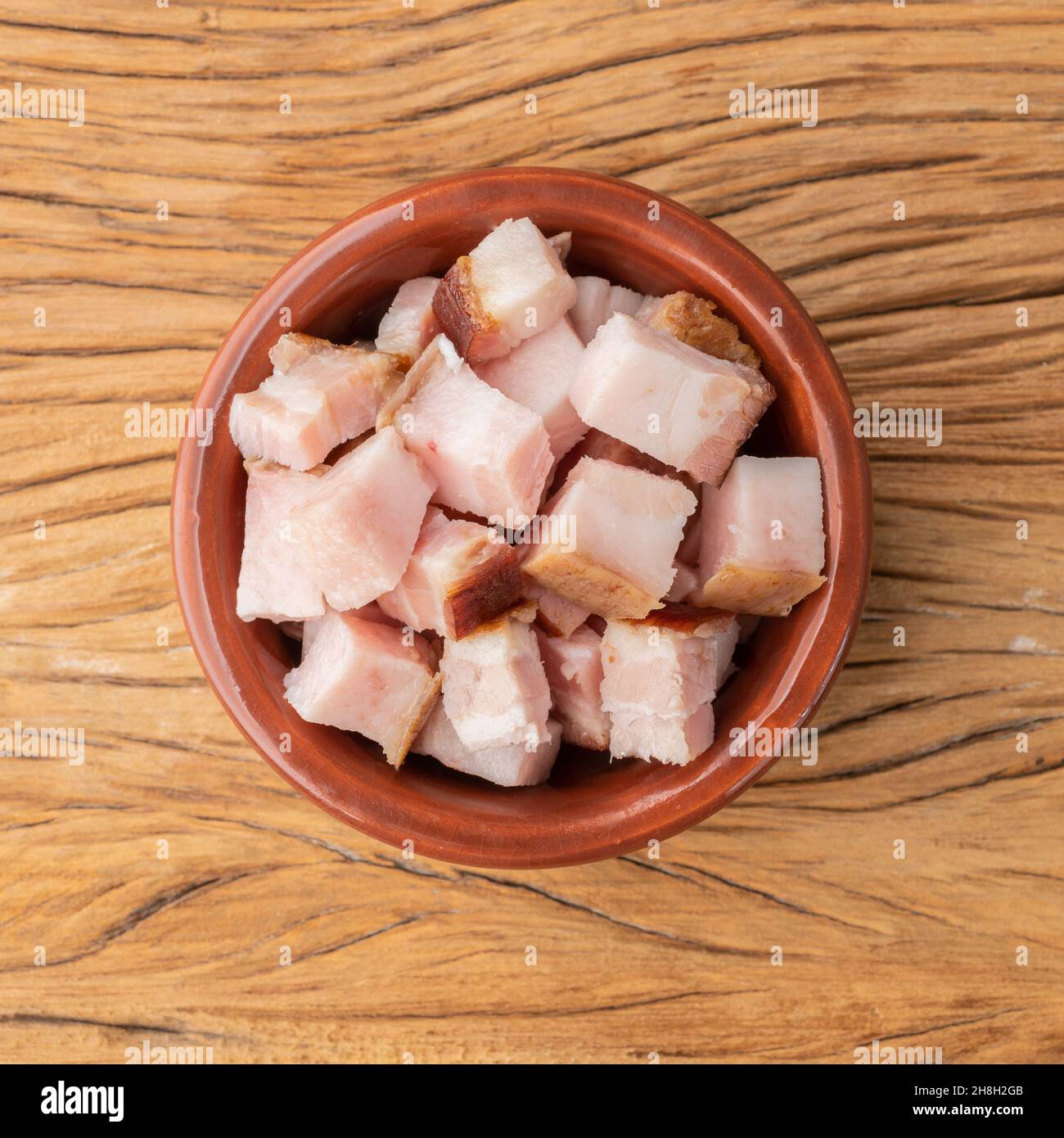 Cubes de bacon fumé dans un bol sur planche de bois. Banque D'Images