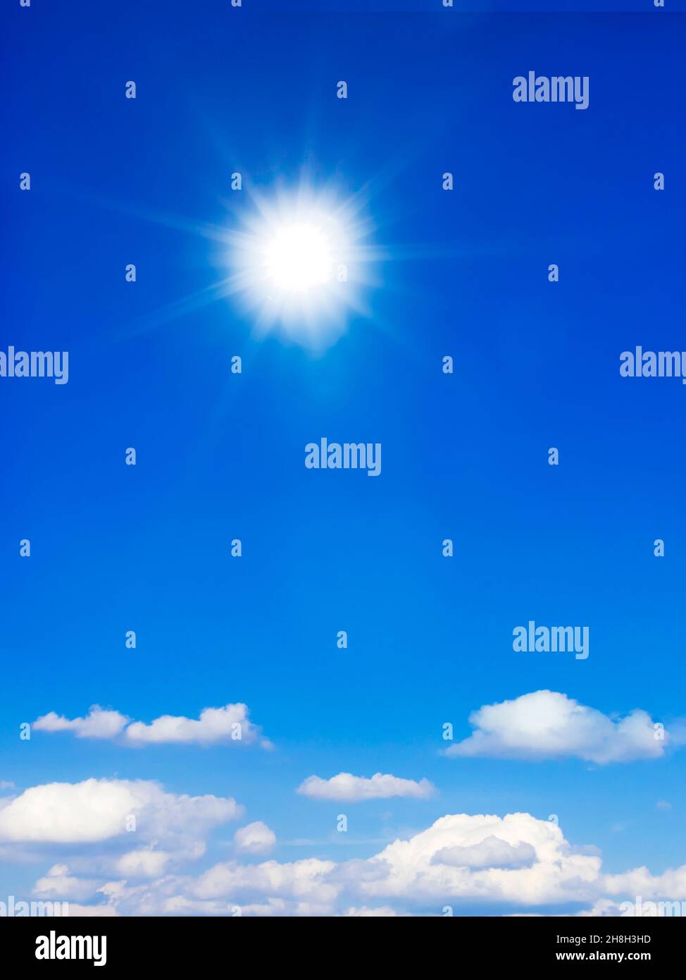 Soleil d'été dans un ciel bleu vif avec quelques nuages moelleux, arrière-plan, orientation verticale. Banque D'Images