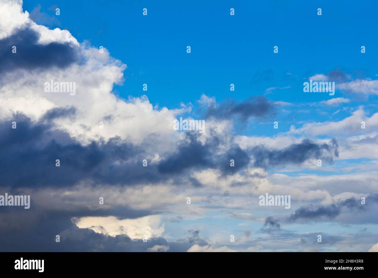 Lumière spectaculaire et nuages sombres contre un ciel bleu d'été.Texture d'arrière-plan du concept d'atmosphère dangereuse. Banque D'Images