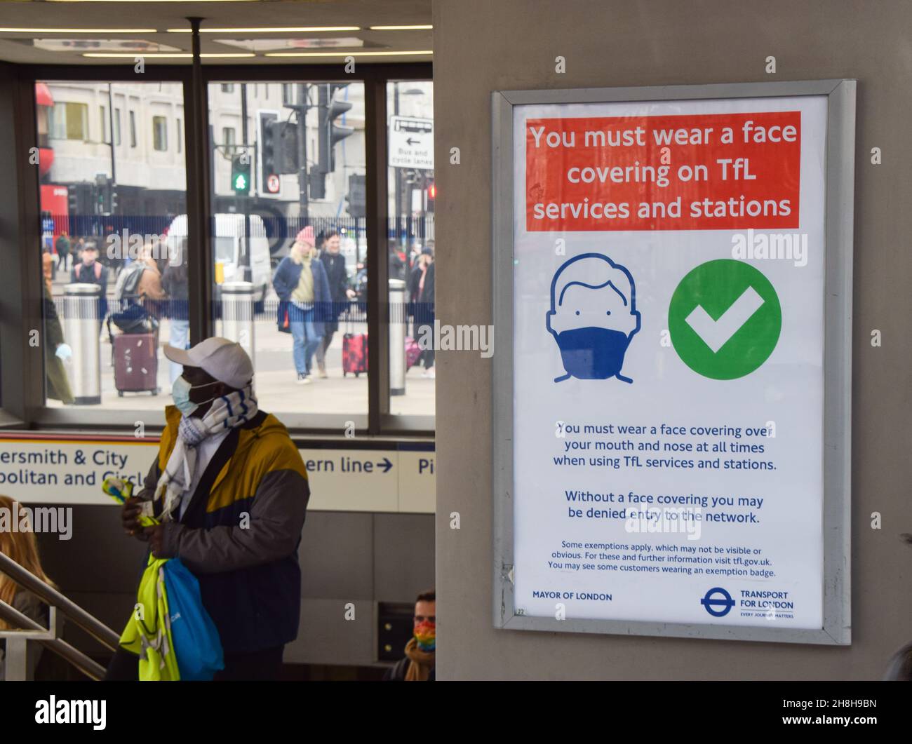 Londres, Royaume-Uni.30 novembre 2021.Un train de banlieue passe devant un panneau à l'extérieur de la station de métro King's Cross St Pancras.Des restrictions concernant les coronavirus ont été réintroduites au Royaume-Uni, avec des masques obligatoires dans les magasins et dans les transports publics, pour aider à stopper la propagation de la nouvelle variante d'Omicron.Les personnes qui refusent de porter des masques sont confrontées à une amende de £200. Banque D'Images