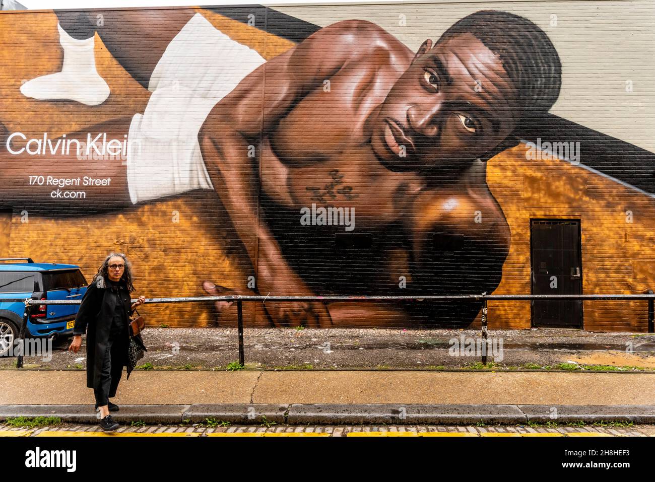 Une femme afro-caribéenne passe devant Street Art/Graffiti, Shoreditch, Londres, Royaume-Uni. Banque D'Images