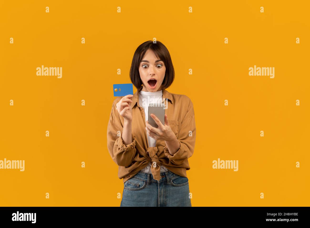 Concept bonus et cashback.Surprise jeune femme montrant carte de débit de crédit, en utilisant le smartphone, en faisant le paiement en ligne Banque D'Images