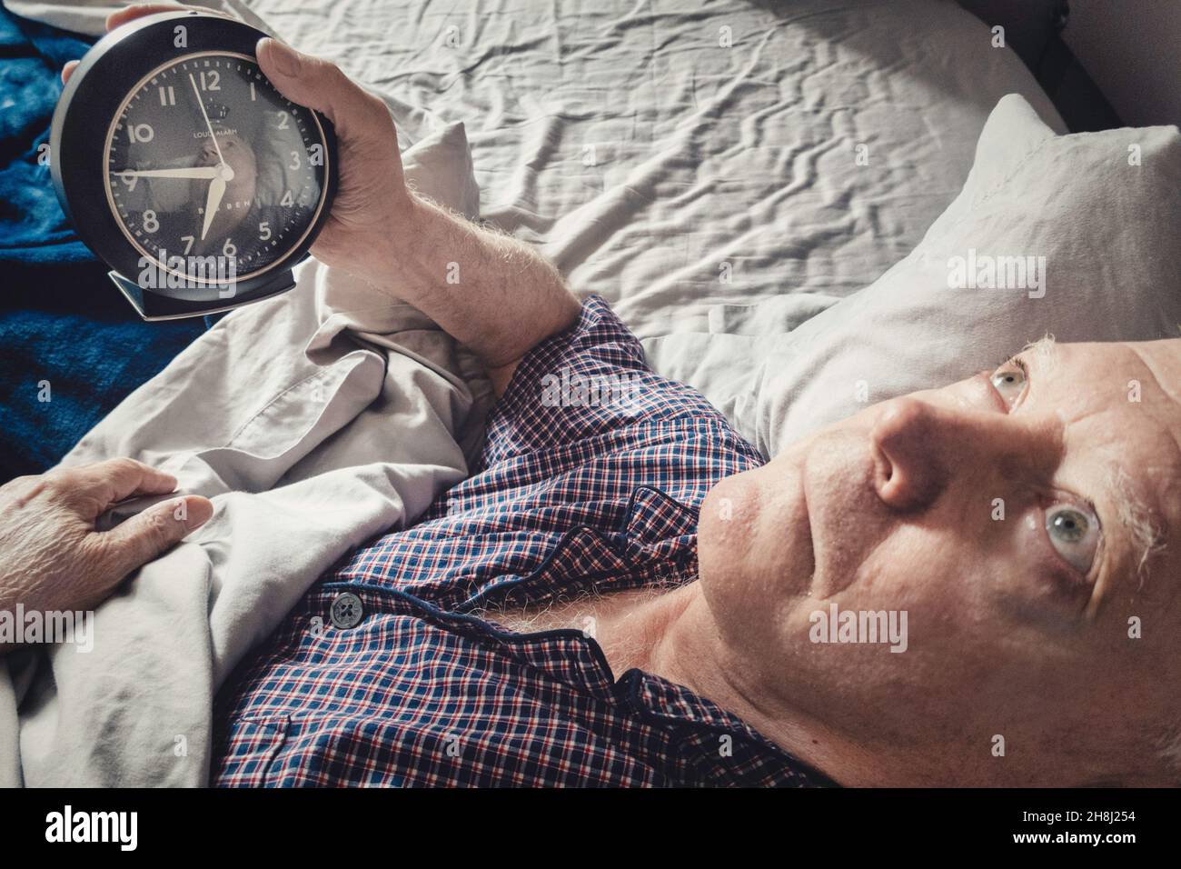 Homme mature sans sommeil, lancer et tourner, regardant horloge, USA 2021 Banque D'Images