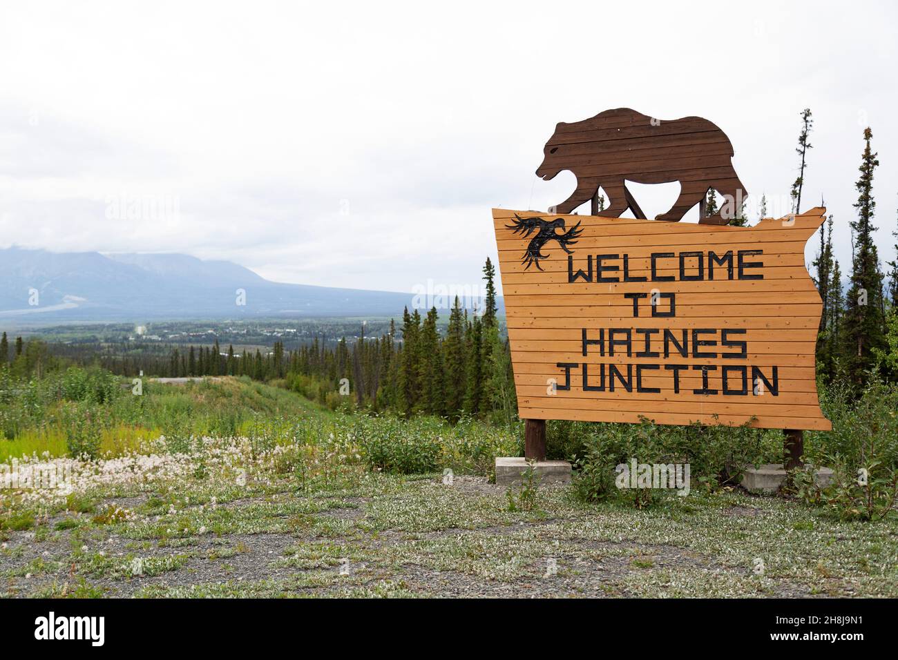 Panneau pour Haines Junction au sud-ouest du Yukon, Canada.Le panneau en bois présente une figure représentant un grizzli. Banque D'Images