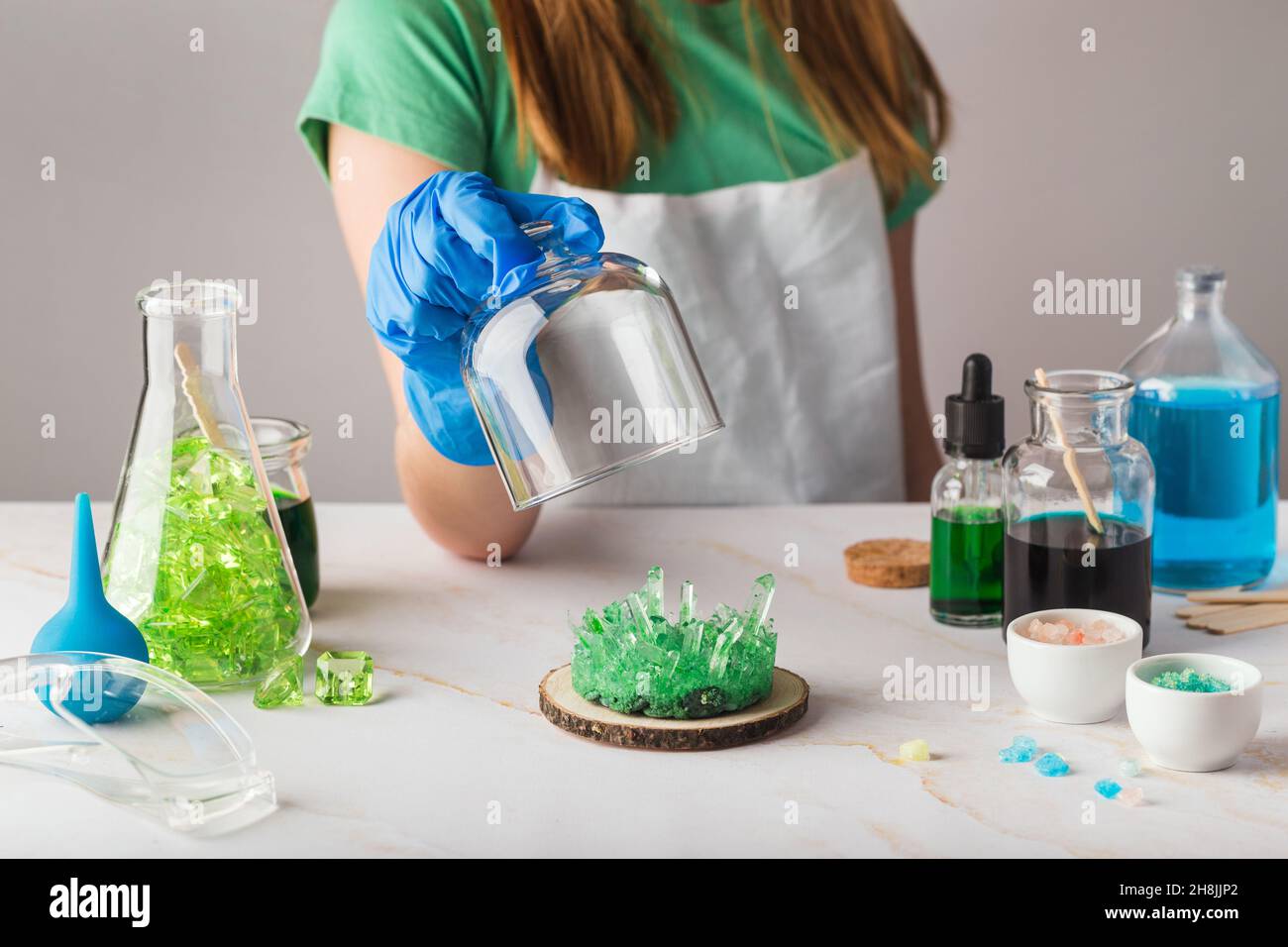 Jolie fille en lunettes de chimie impressionnée par la croissance de cristal vert.La science est un concept amusant avec les enfants à la maison Banque D'Images