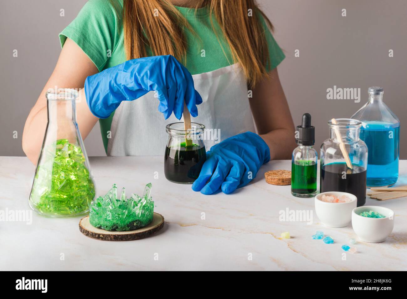 Jolie fille en lunettes de chimie impressionnée par la croissance de cristal vert.La science est un concept amusant avec les enfants à la maison Banque D'Images