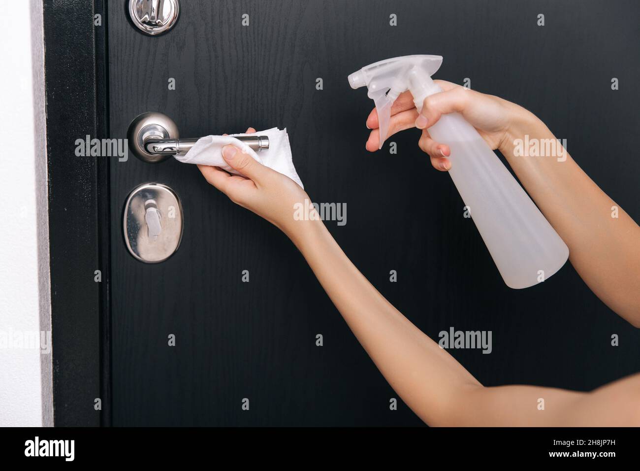 Nettoyage des poignées de porte noires avec une lingette humide antiseptique.Femme main utilisant une serviette pour nettoyer la liaison de la porte de la chambre à la maison.Désinfectez la prévention des surfaces dans Banque D'Images