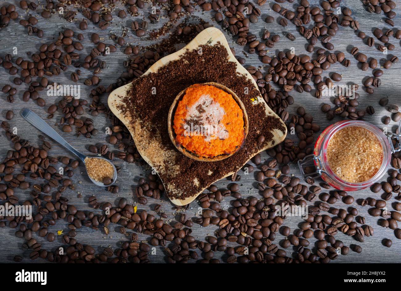 Faire revenir le sucre dans un pot en verre et une cuillère en acier, un gâteau aux carottes, des grains de café moulus et des grains de café sur fond de bois Banque D'Images