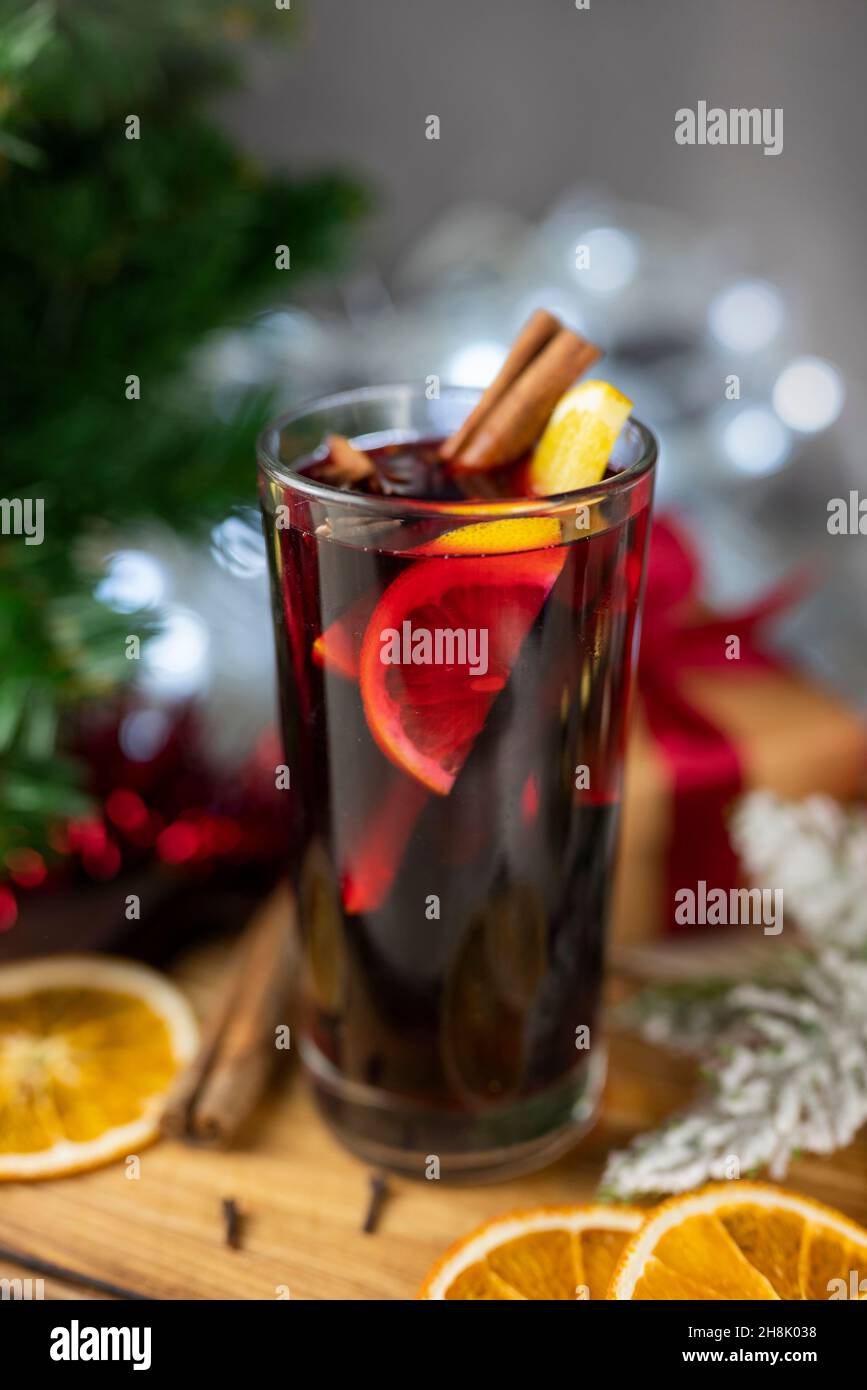 Délicieux vin chaud rouge chaud et épicé aux épices d'orange et de cannelle près de l'arbre de Noël avec des décorations et des guirlandes de bokeh Banque D'Images