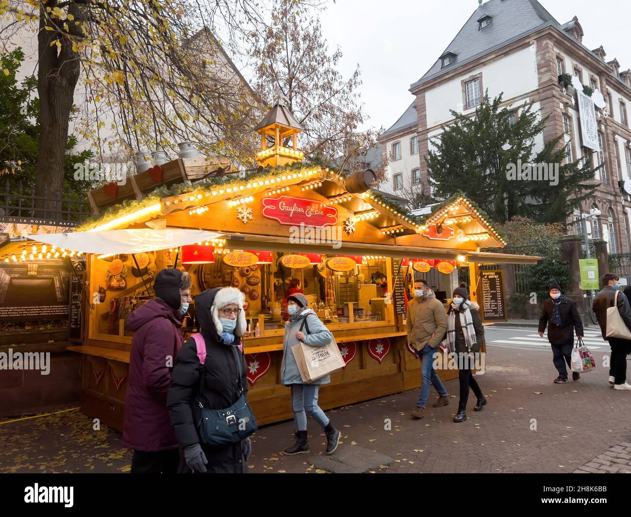 Personnes avec des masques en face des étals du marché chalets vendant des souvenirs de nourriture et de vin chaud Banque D'Images