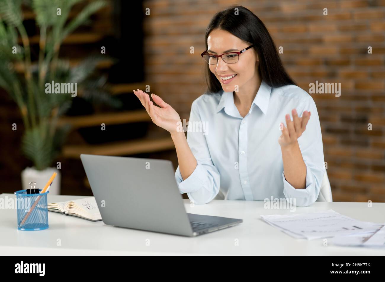 Belle femme d'affaires caucasienne confiante, pigiste, Manager, en utilisant un ordinateur portable, en discutant sur vidéo conférence avec le client ou collègue, en discutant de projet d'affaires, en faisant des gestes avec la main, sourires Banque D'Images