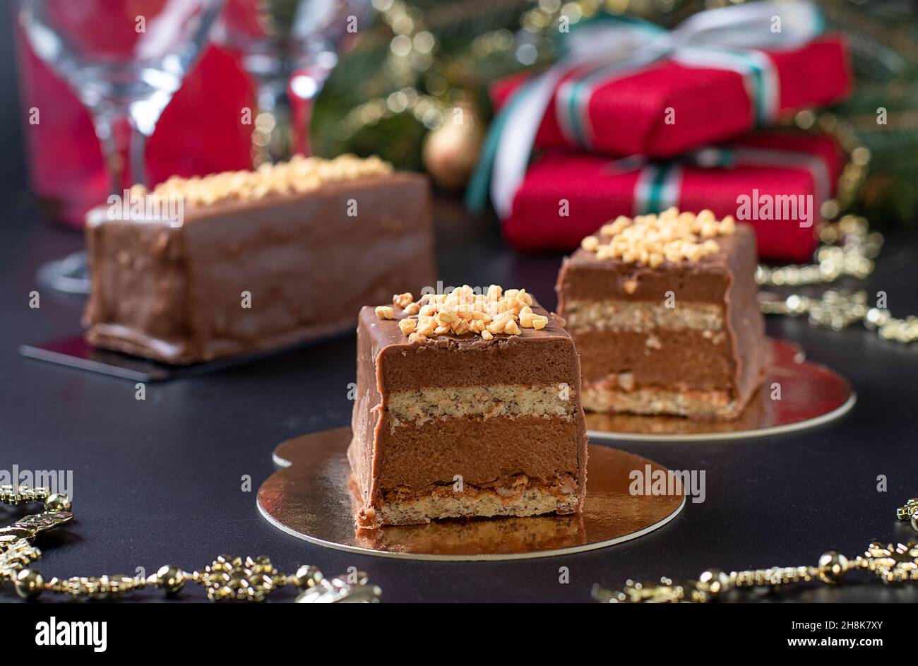 Desserts à la mousse en tranches avec praline de noisette, chocolat au lait et glaçage gourmand au chocolat et aux noix sur fond de nouvel an, gros plan Banque D'Images