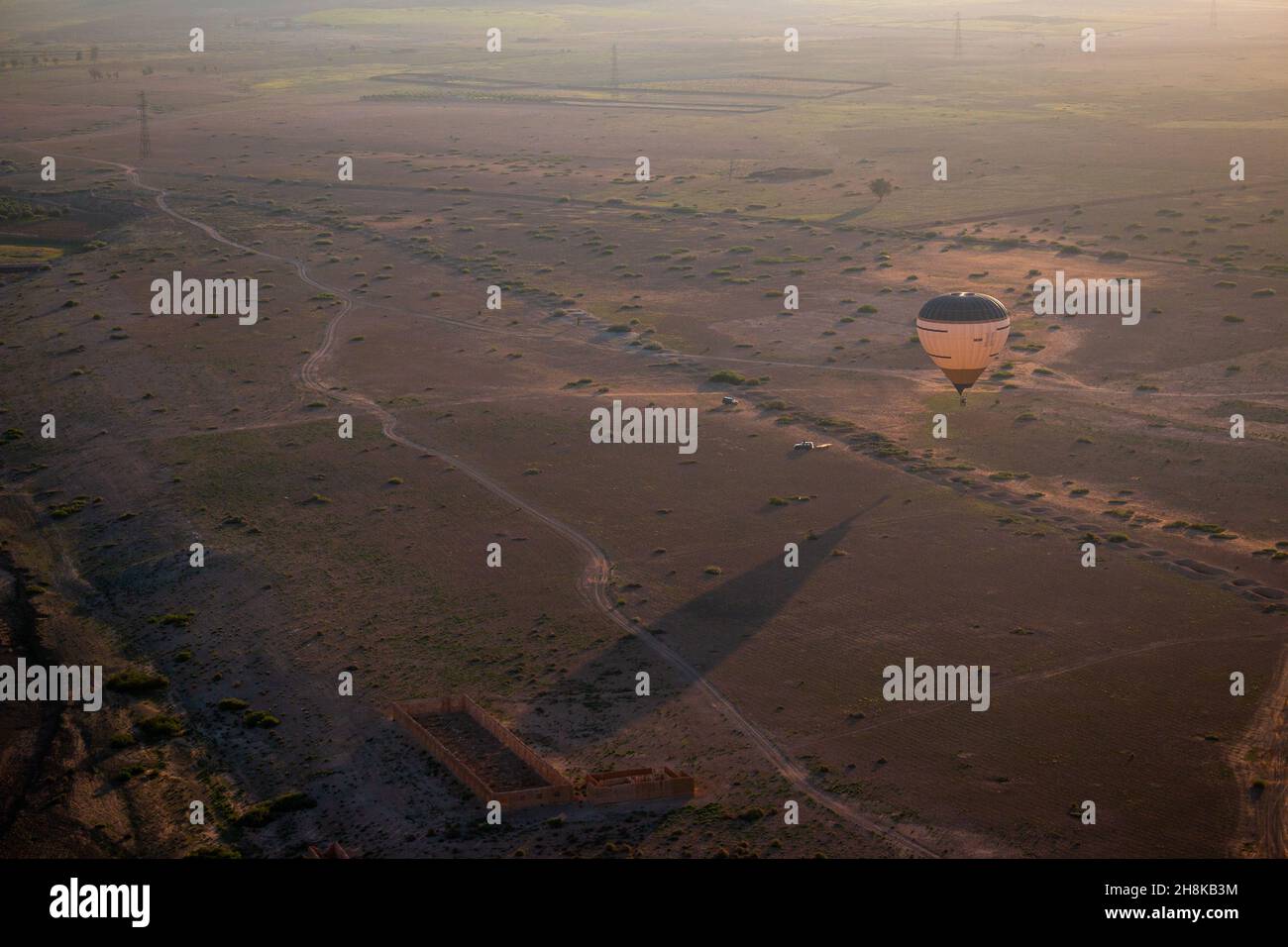 Un ballon d'air chaud et sa longue ombre au lever du soleil dans le désert du Maroc, une visite près de Marrakech. Banque D'Images