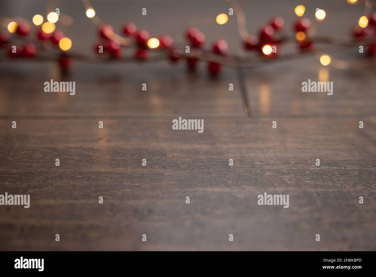 Bordure de baies de houx rouges vibrantes avec une série de lumières de Noël blanches sur un fond en bois sombre avec espace de copie Banque D'Images