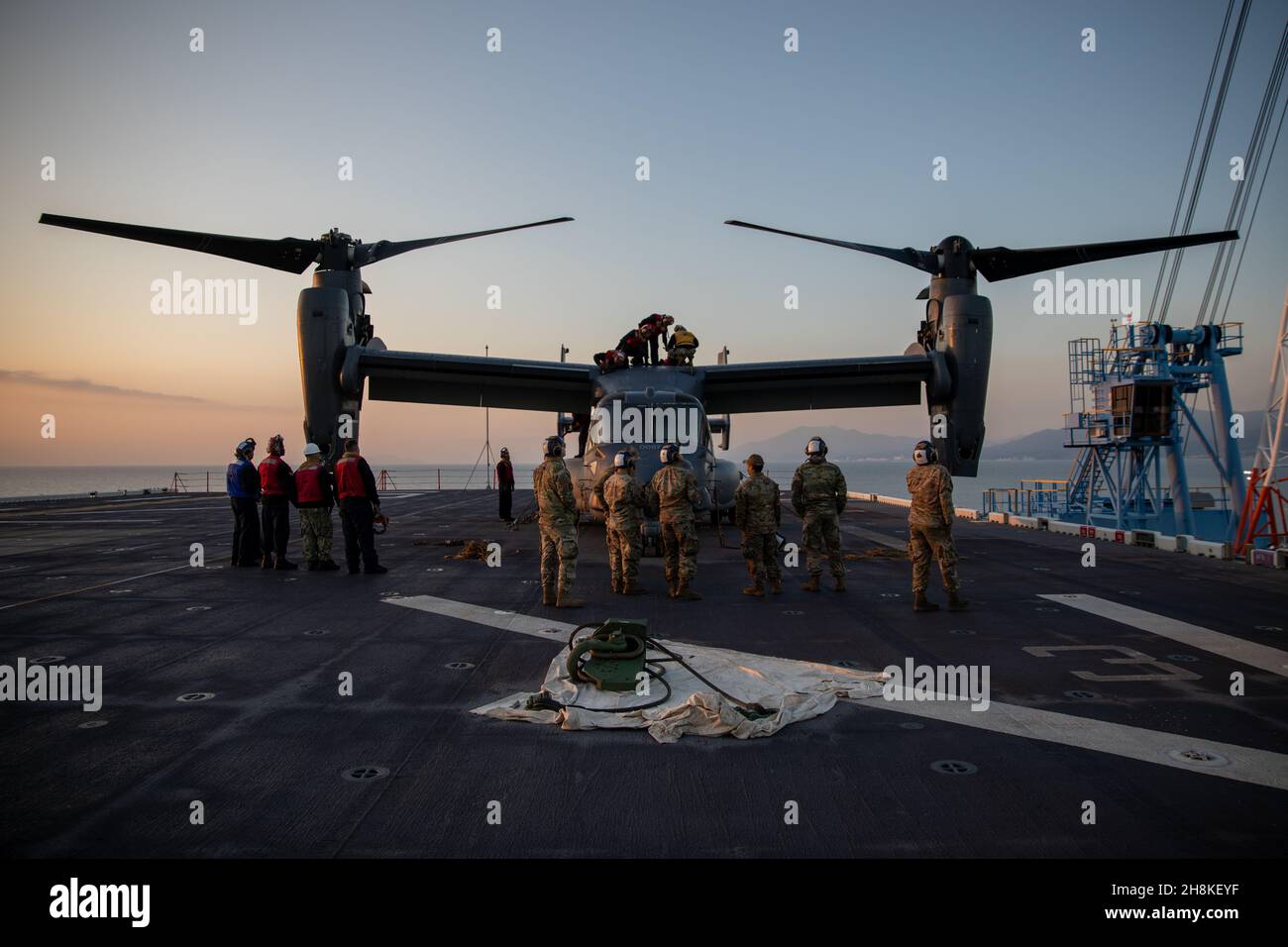 Des marins et des aviateurs américains préparent un CV-22 Osprey pour le transfert à la station aérienne du corps des Marines Iwakuni, ligne de vol du Japon, 19 novembre 2021.L’avion était à bord de l’USS America (LHA 6) alors que le navire était amarré au port en eau profonde du MCAS Iwakuni.En raison de sa situation géographique et de sa co-localisation du terrain d'aviation et du port, la station aérienne est unique en son genre pour fournir une intégration navale avancée à l'appui de la sécurité régionale.(U.S. photo du corps des Marines par lance Cpl.Isaac Orozco). Banque D'Images