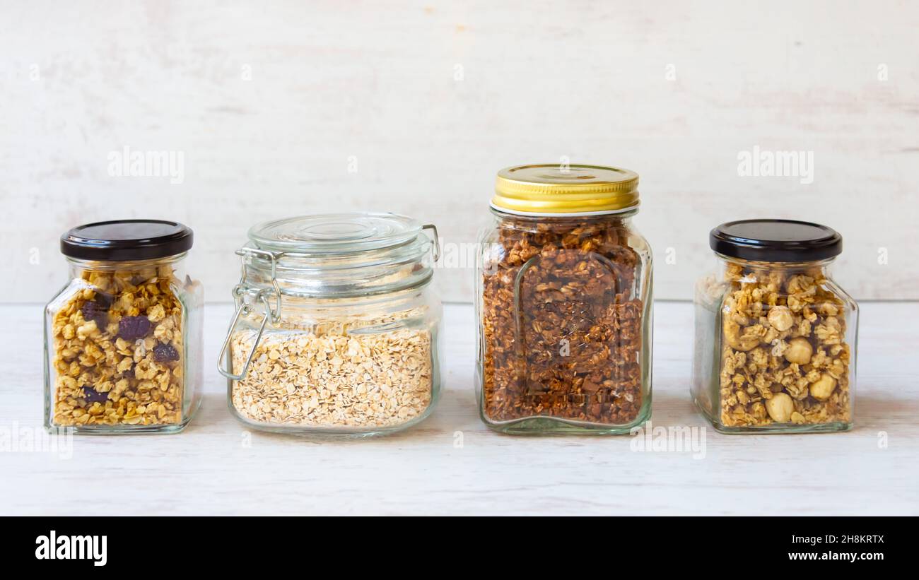 Bocaux pleins d'avoine et divers granola croquant - simple, fruits secs, noix et chocolat.Concept de repas de grande qualité. Banque D'Images