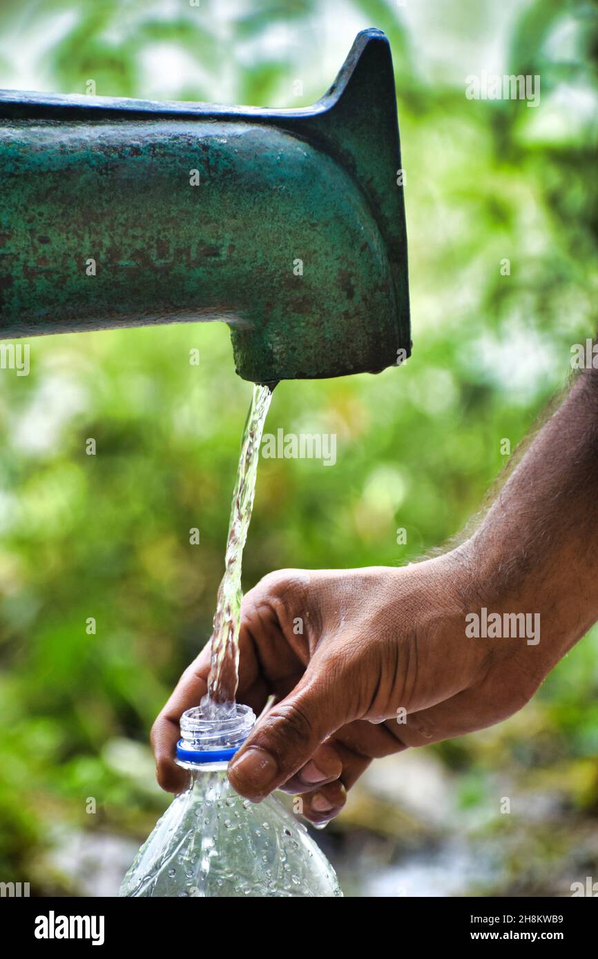 Un homme a rempli l'eau dans une bouteille de la source d'eau tarditionnelle appelée tube Well. Banque D'Images